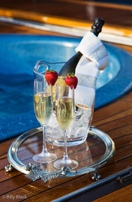 Botle of champagne accompanied by two glasses being served poolside